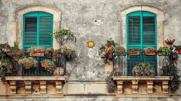 Historische italienische Hausfassade mit grünen Fensterläden und bepflanzten Balkonen